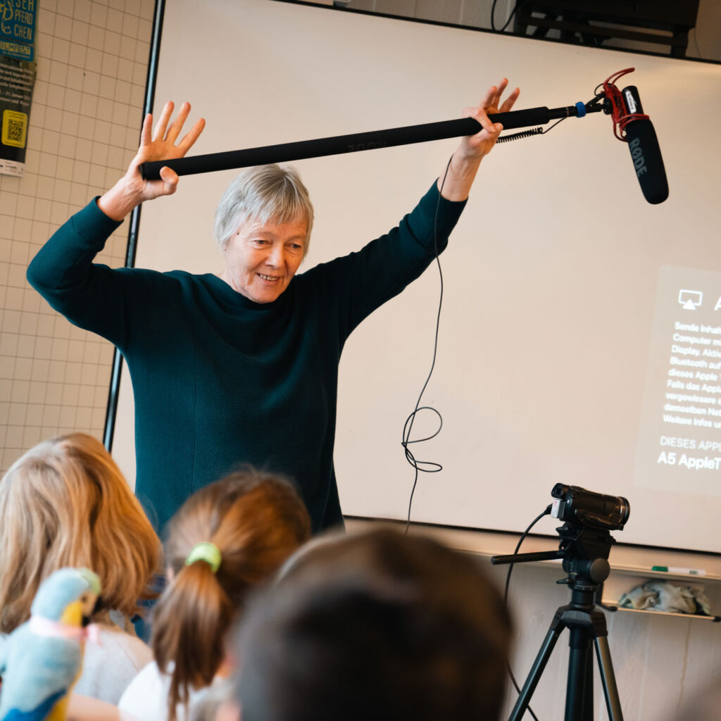 Medienpädagogin mit Mikrofon bei einem Projekt in der Schule