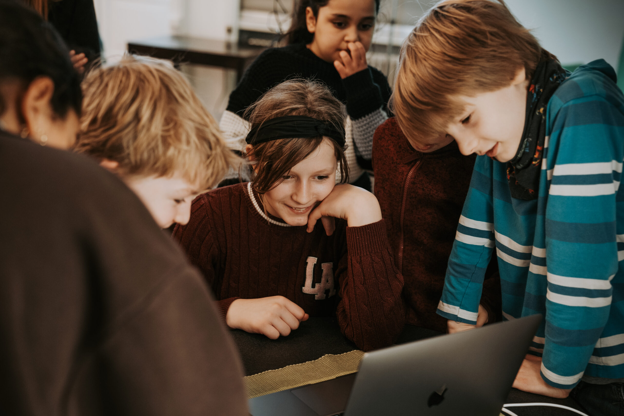 Mehrere Kinder schauen begeistert auf einen Laptop-Bildschirm.